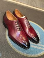 Chaussures Richelieu Jespomi pour homme en cuir bordeaux patiné, modèle One-Cut avec dégradé noir au bout, posées sur un tapis bleu et gris.