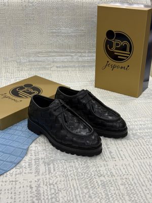 Chaussures Derby noires en cuir tressé avec semelle crantée robuste, présentées devant les coffrets de la marque Jespomi.