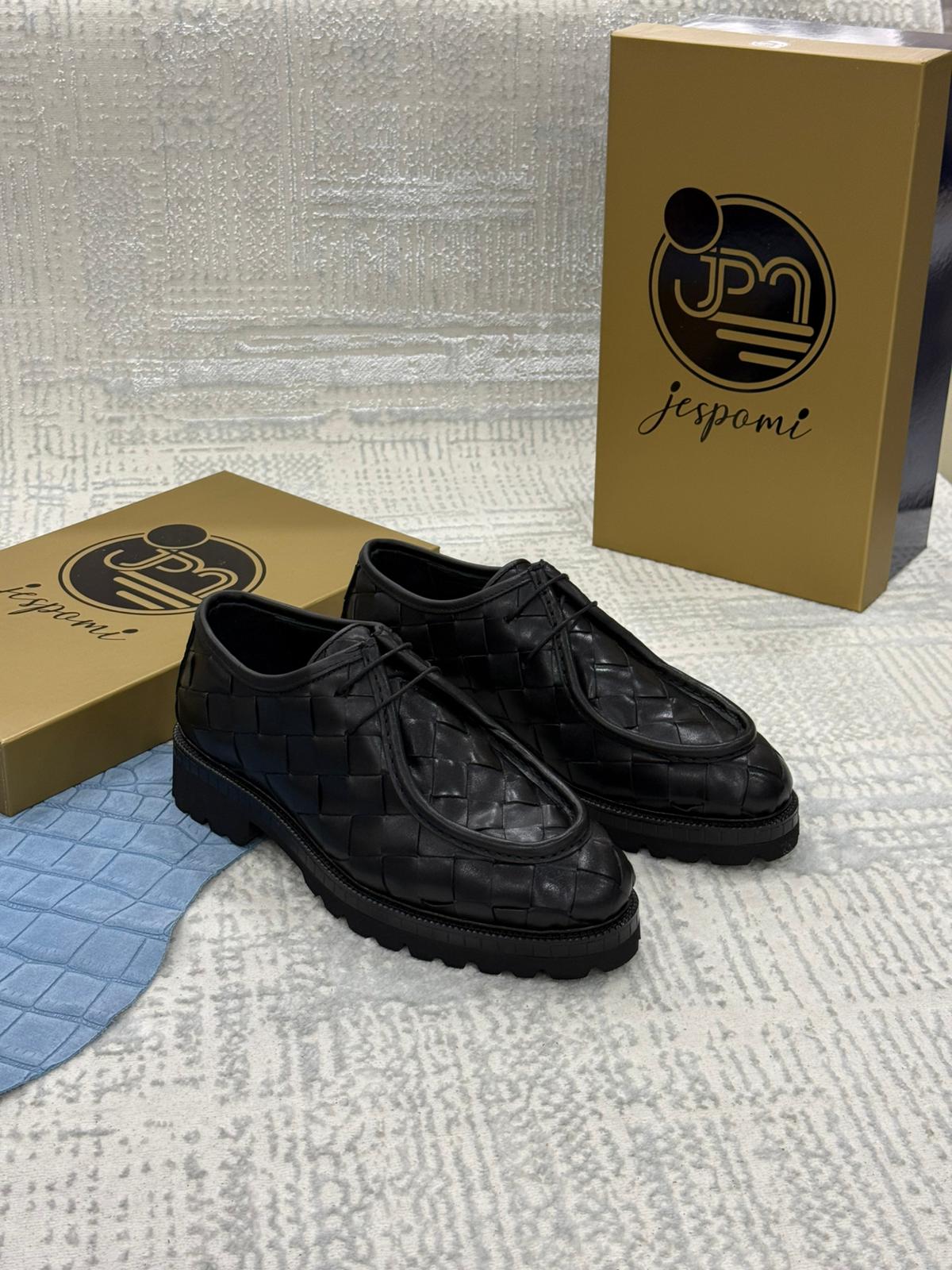 Chaussures Derby noires en cuir tressé avec semelle crantée robuste, présentées devant les coffrets de la marque Jespomi.