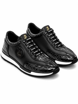 Sneakers de luxe Jespomi en cuir noir mat et empiècements en cuir façon crocodile brillant avec logo doré sur la languette.