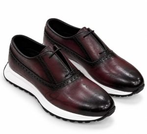 Chaussures Richelieu homme bordeaux foncé et noir à motifs décoratifs, perforations brogue et semelle blanche contrastante.